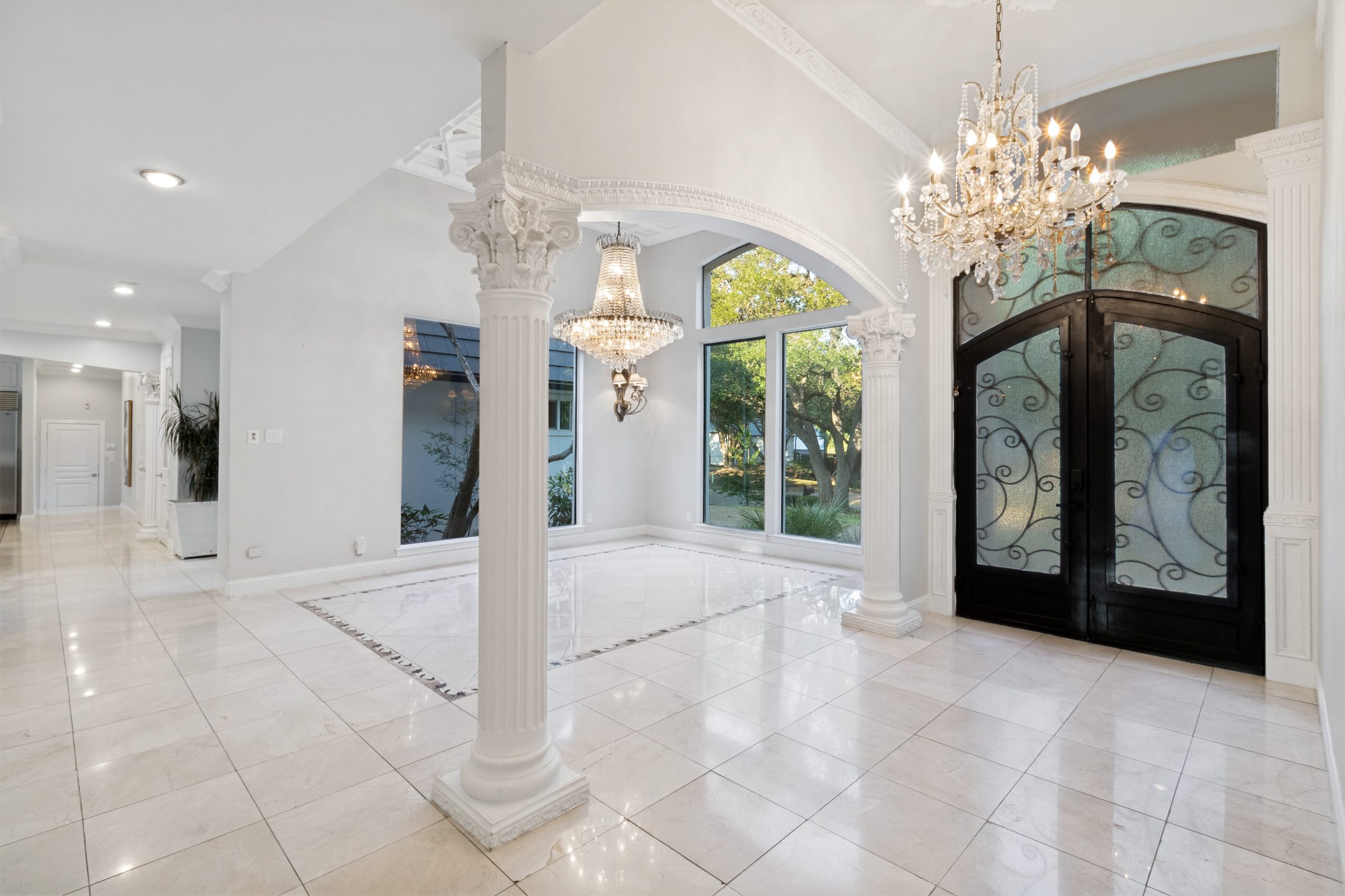 Grand entry foyer with marble flooring, columns and crystal chandeliers