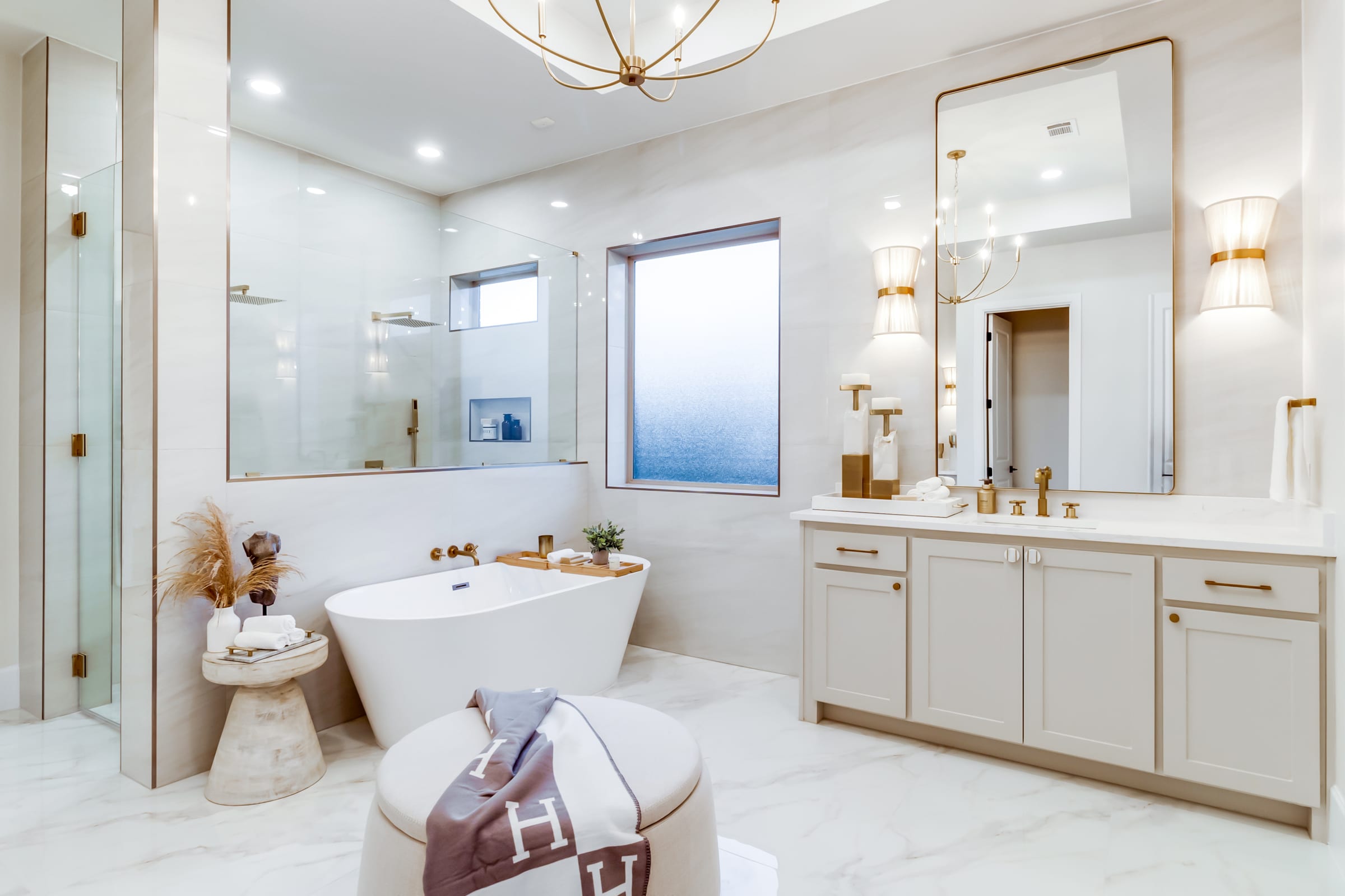 Luxury primary bathroom with freestanding soaking tub and brass fixtures